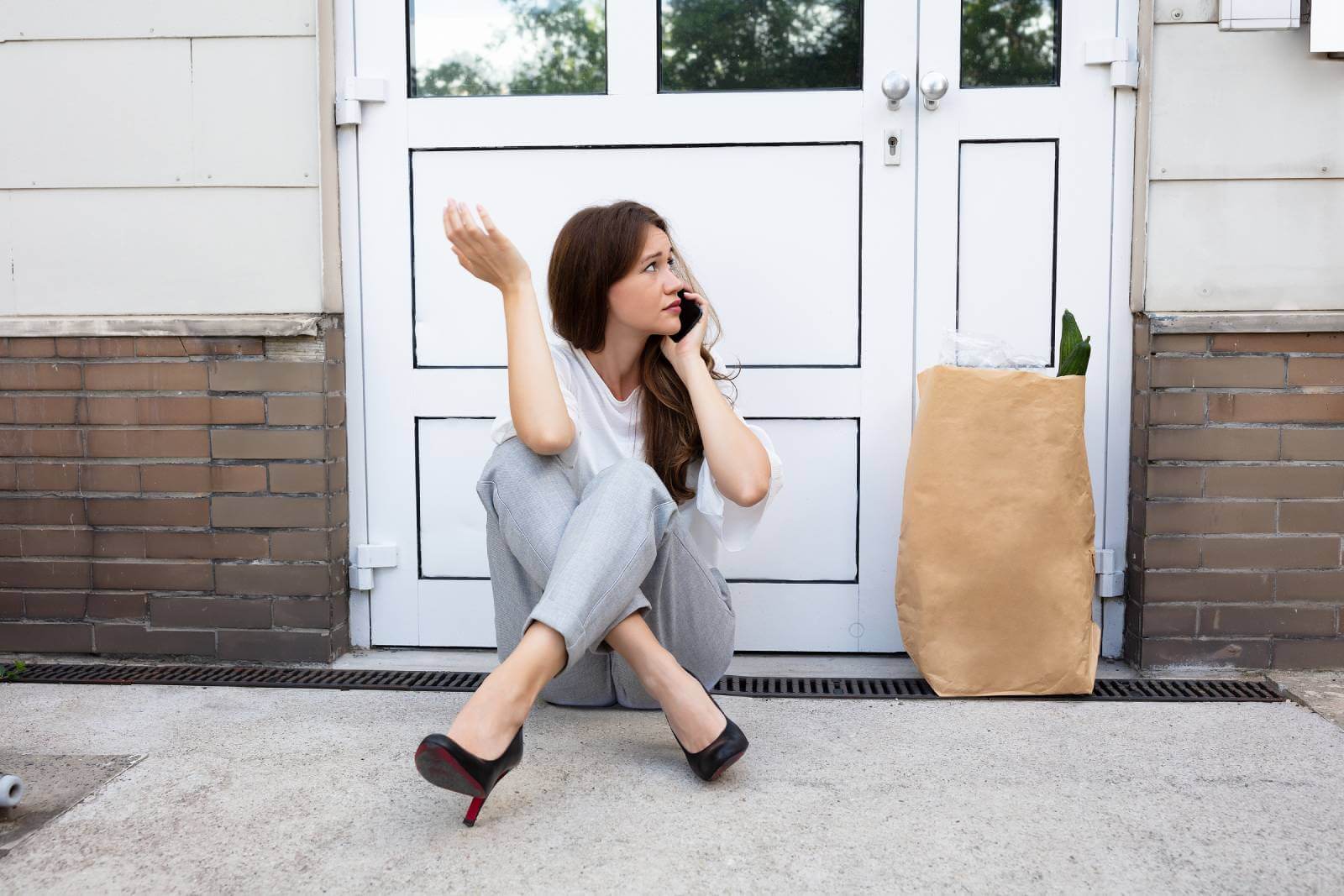 A frustrated woman sitting outside a locked house, making a phone call for house lockout service in Mississauga Valleys by Mississauga Locksmiths. A frustrated woman sitting outside a locked house, making a phone call for house lockout service in Mississauga Valleys by Mississauga Locksmiths.