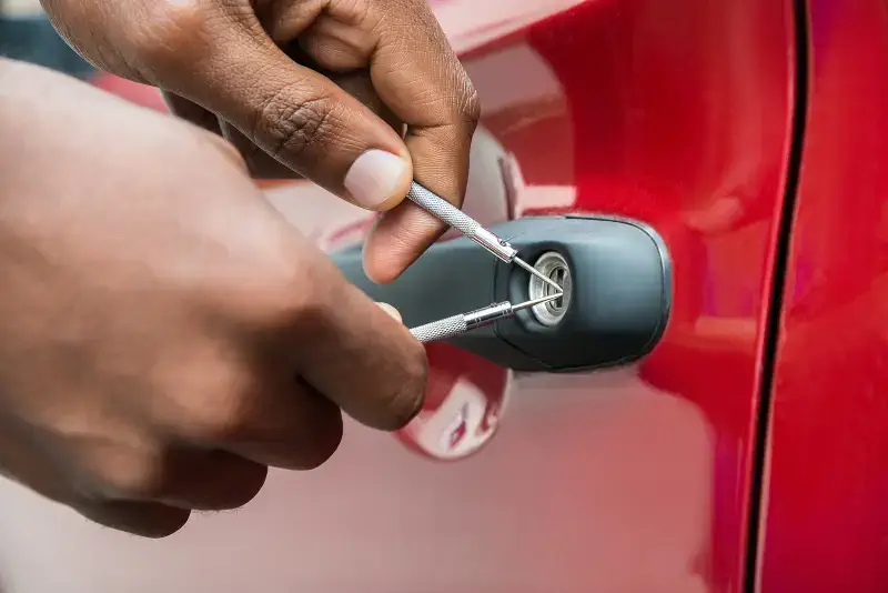 Mississauga Locksmith providing professional automotive locksmith services in Port Credit, using specialized tools to unlock a red car door without damage. Automotive Locksmith in Mississauga: Car Key Replacement & Programming Explained